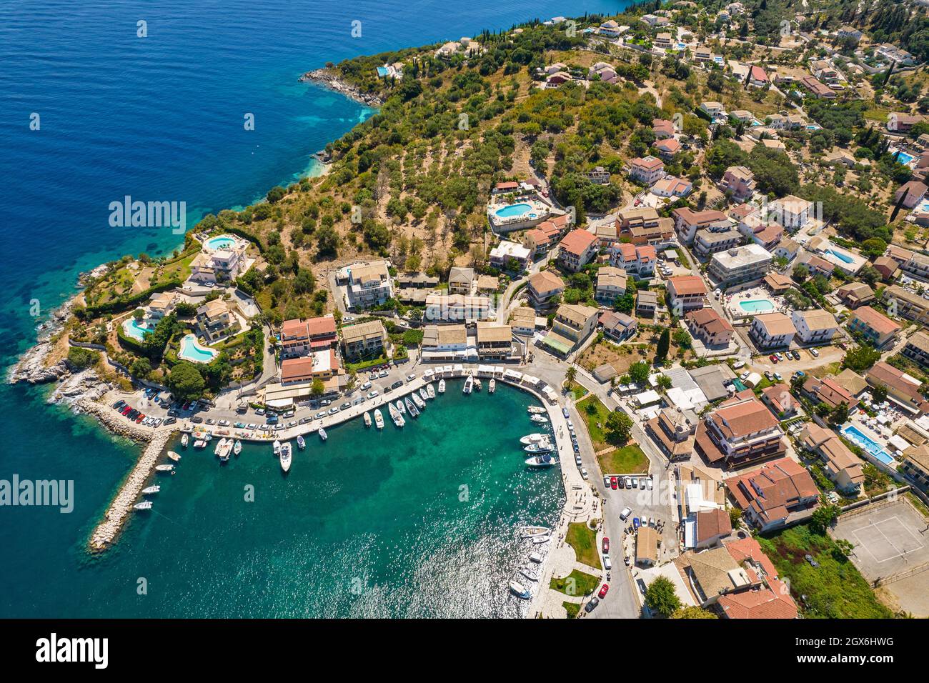 Vista aerea del drone sulla marina di Kassiopi, il piccolo porto iconico e il villaggio di pescatori a nord dell'isola di Corfù, in Grecia. Foto Stock