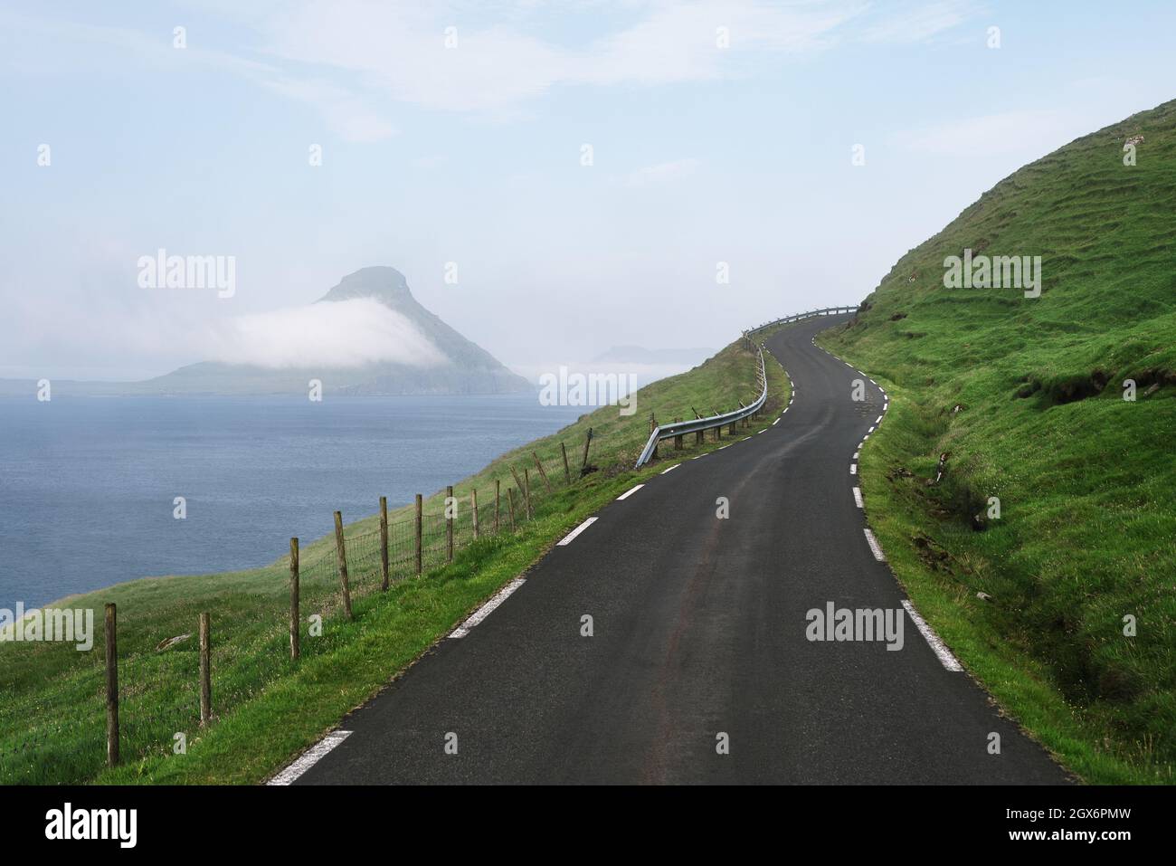Strada sul lato di una collina verde che domina l'isola di Koltur, Isole Faroe Foto Stock