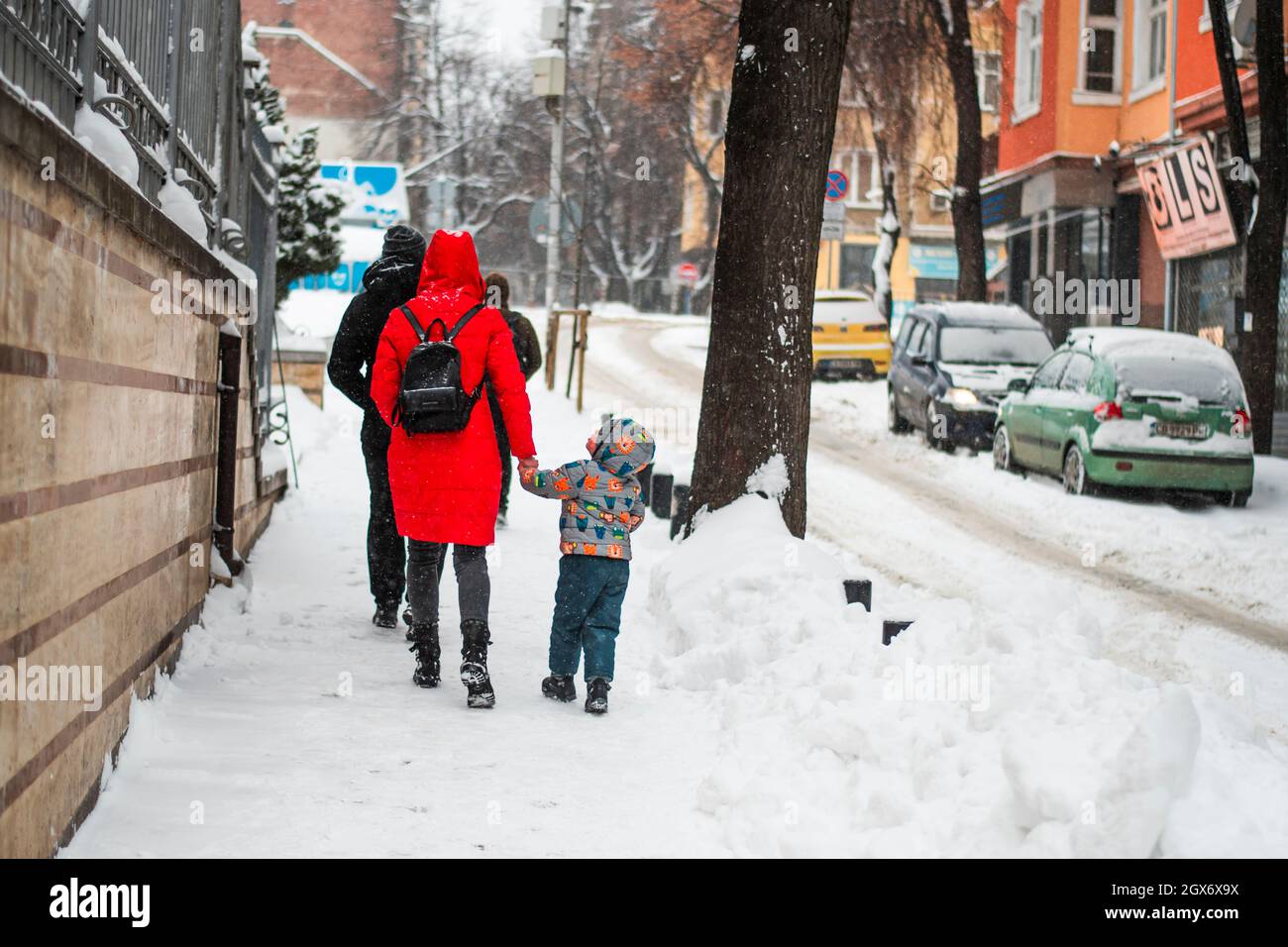 Bulgaria, circa febbraio 2021: Una madre colorata e un bambino che cammina per le strade nevose di Sofia, Bulgaria, Europa. Foto Stock