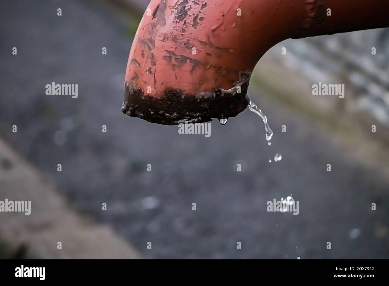 Goccioline d'acqua fluiscono dal vecchio tubo arrugginito. Scarsità d'acqua sul pianeta. Concetto di inquinamento del suolo e problemi di fonti fossili. Foto Stock