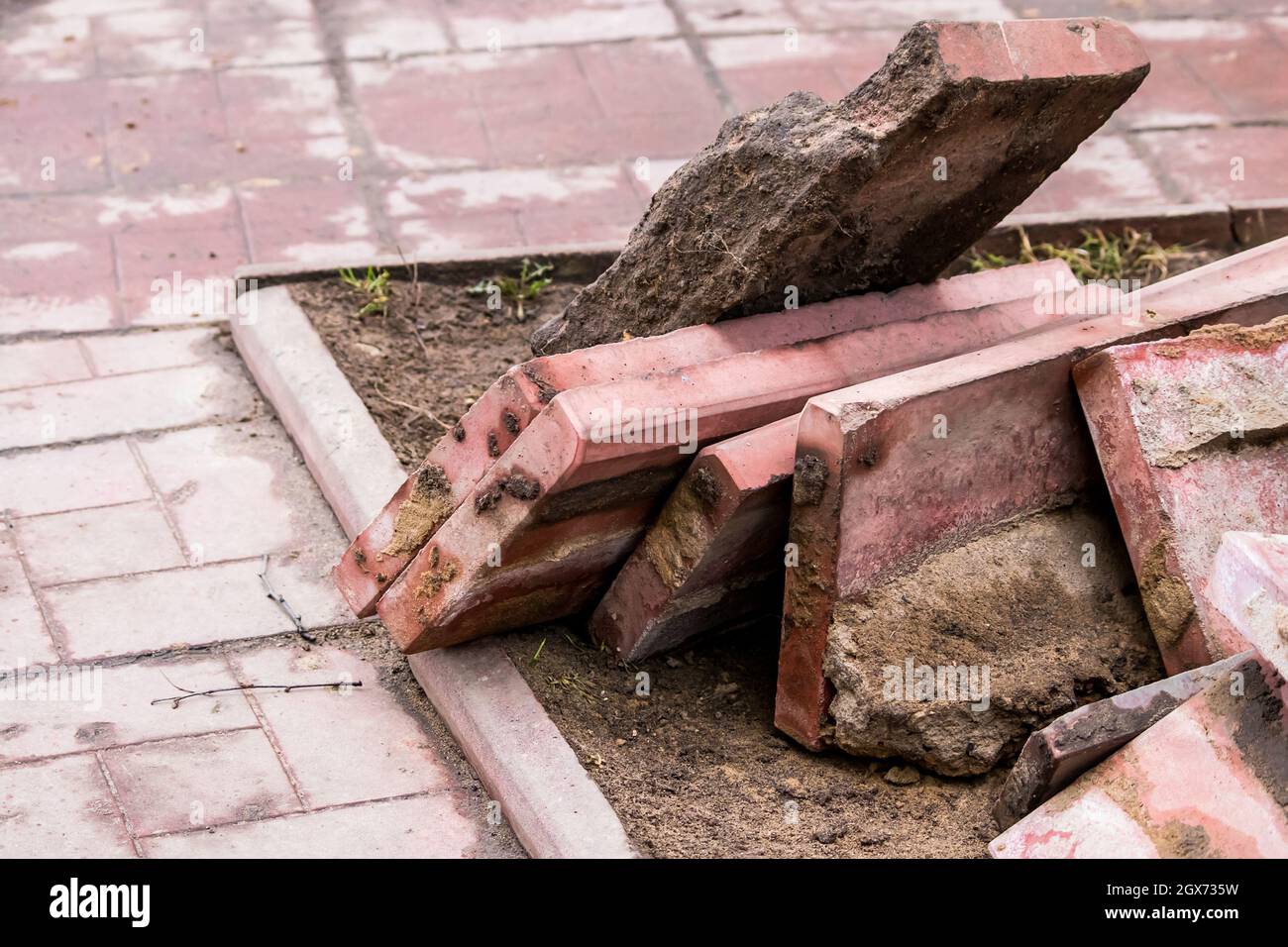 Vecchie lastre di pavimentazione in pietra rotta. Riparazione del marciapiede in città. Foto Stock