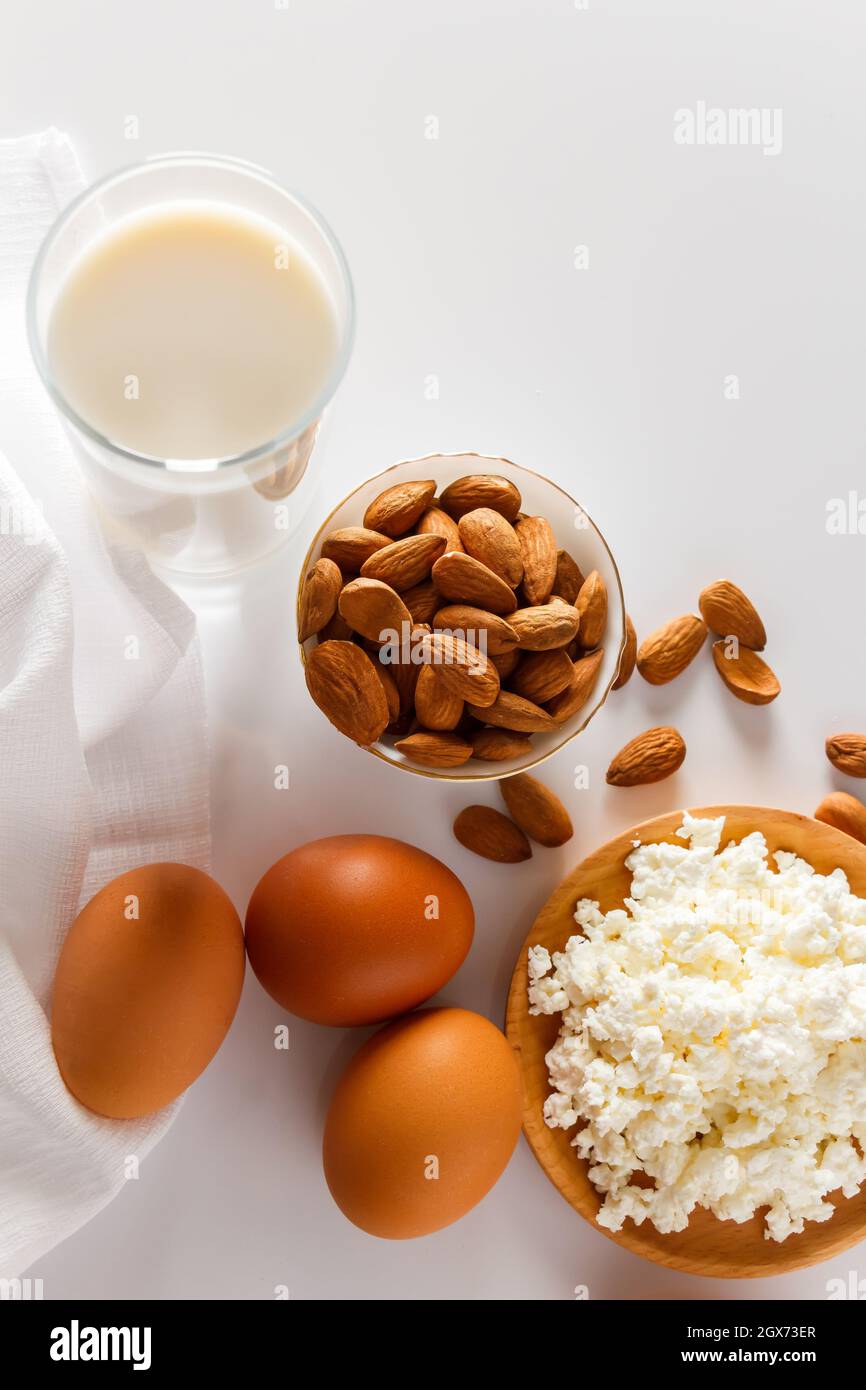 Un insieme di alimenti proteici sani per una dieta equilibrata. Ricotta formaggio, uova e noci su sfondo bianco. Foto Stock Un insieme di alimenti proteici sani per una dieta equilibrata. Ricotta formaggio, uova e noci su sfondo bianco. Foto Stock