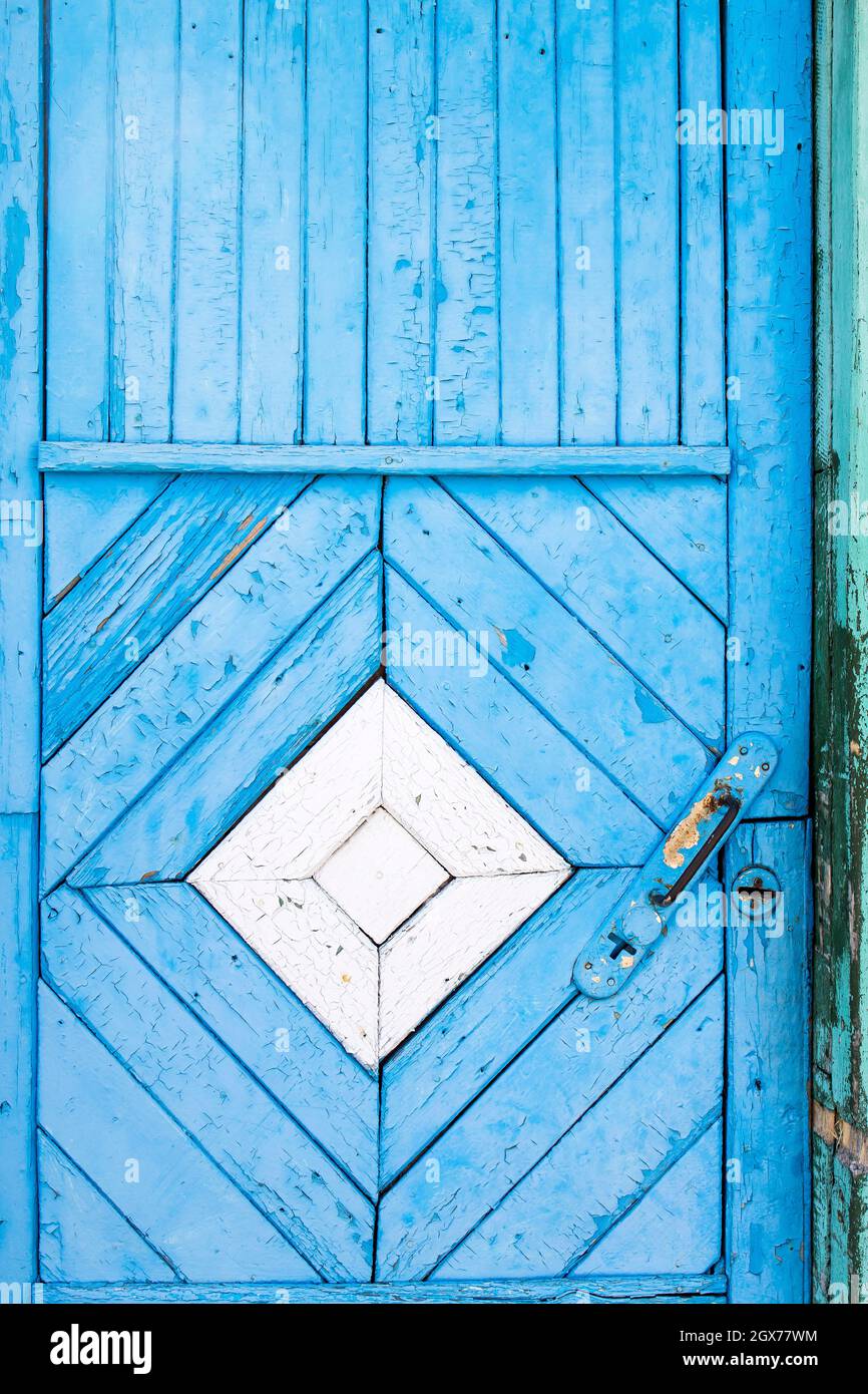 Una porta di legno blu, con un rombo bianco al centro, fatta di tavole. Dettagli Foto Stock