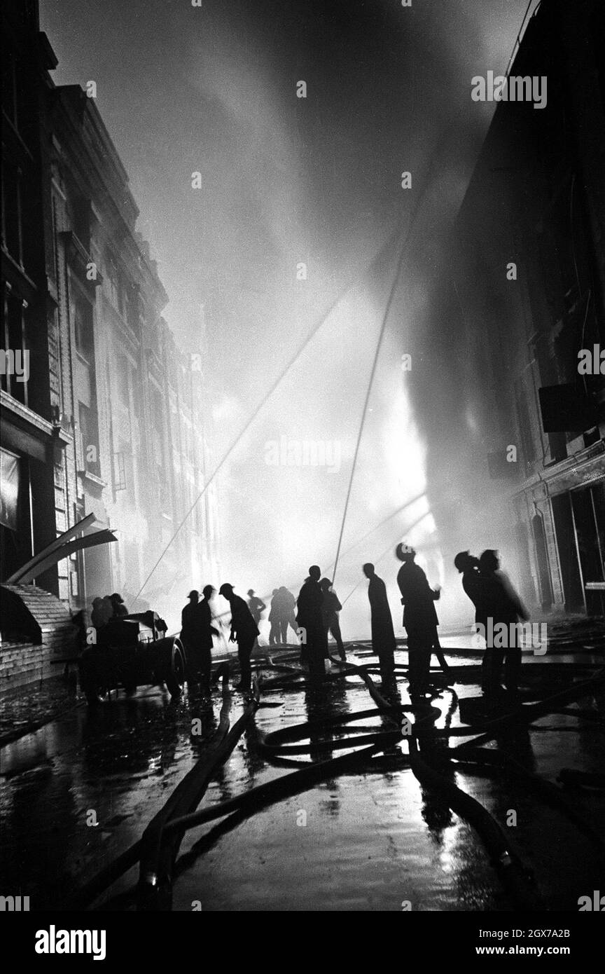 Vigili del fuoco che sparano acqua sugli edifici in fiamme durante il London Blitz Foto Stock