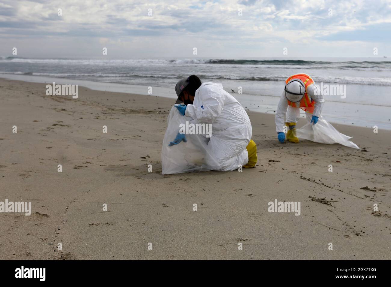 Los Angeles, Stati Uniti. 5 ottobre 2021. I membri del gruppo di pulizia raccolgono olio dalla sabbia a Huntington Beach, Orange County, California, Stati Uniti, 4 ottobre, 2021. Una massiccia fuoriuscita di petrolio al largo della costa della contea di Orange, nella California meridionale, ha provocato la chiusura di un'area di spiaggia lunga 9 chilometri la domenica, e gli equipaggi del California Department of Fish and Wildlife (CDFW) stanno ripulendo l'inquinamento dalle strutture nelle acque federali. Credit: Xinhua/Alamy Live News Foto Stock