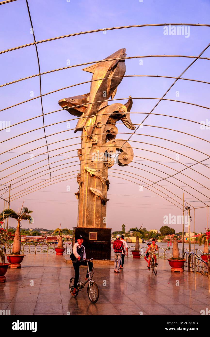 Bambini che giocano intorno ad una grande statua di pesce sulle banchine di Chau Doc nel Mekong. Foto Stock