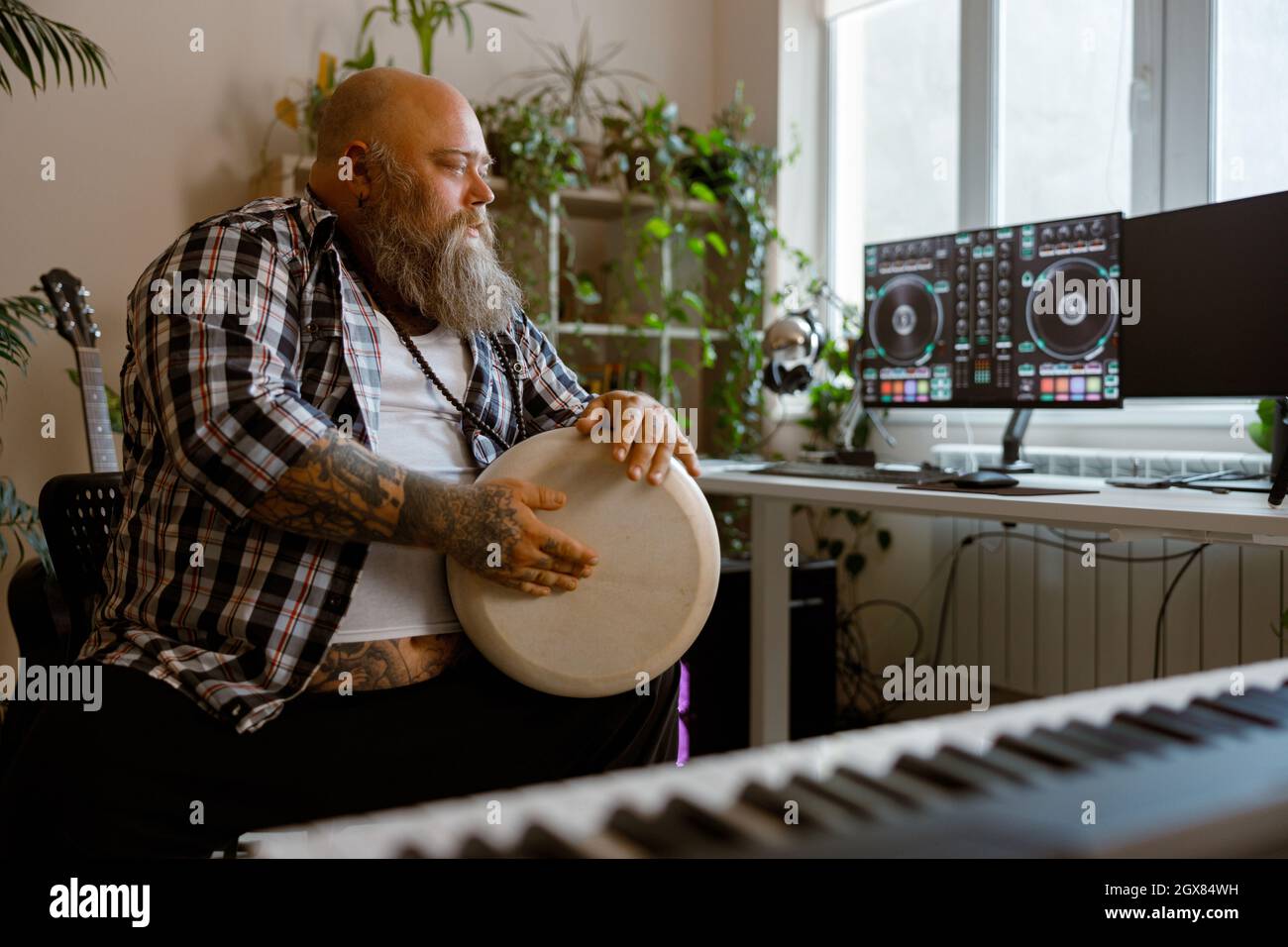 L'uomo di talento gioca a tamburo seduto sul posto di lavoro con monitor di computer in studio Foto Stock
