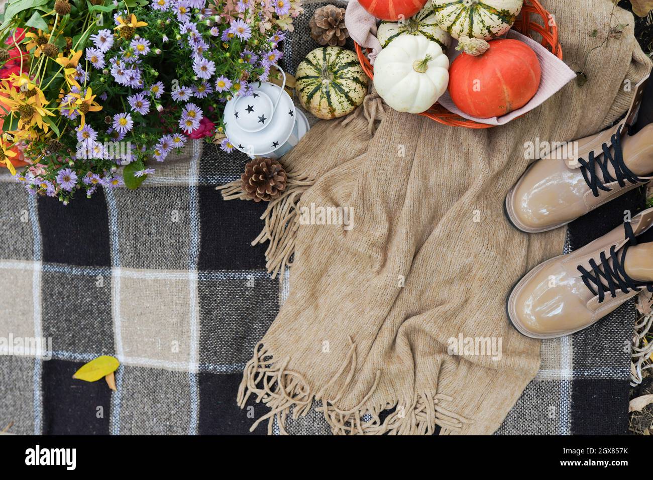 picnic nella foresta autunnale con plaid, fiori, zucche e stivali femminili. vacanza autunnale Foto Stock