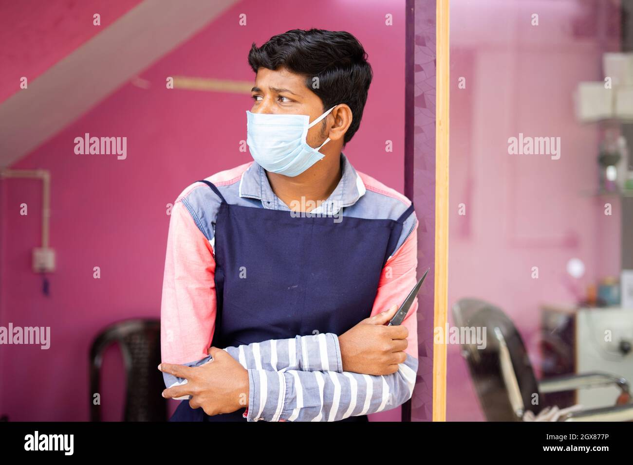 Barbiere con maschera medica in attesa dei clienti dopo la riapertura del negozio durante coronavirus covid-19 pandemic lockdown Foto Stock