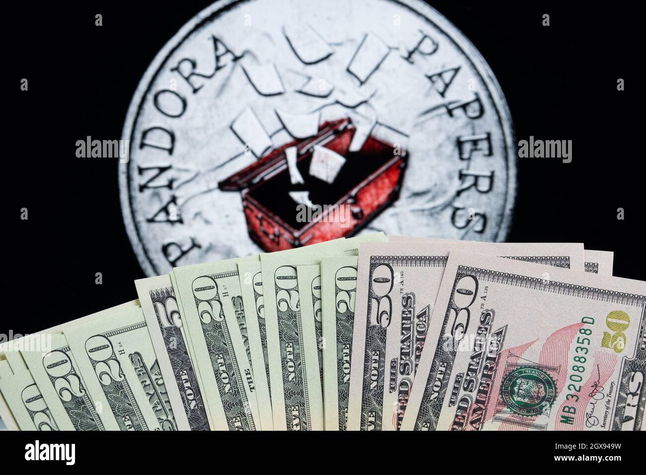 Gettone di denaro e carte di Pandora sfocate, simbolo di documenti fuoriusciti visto sullo schermo dietro. Concetto. Stafford, Regno Unito, 5 ottobre 2021. Foto Stock