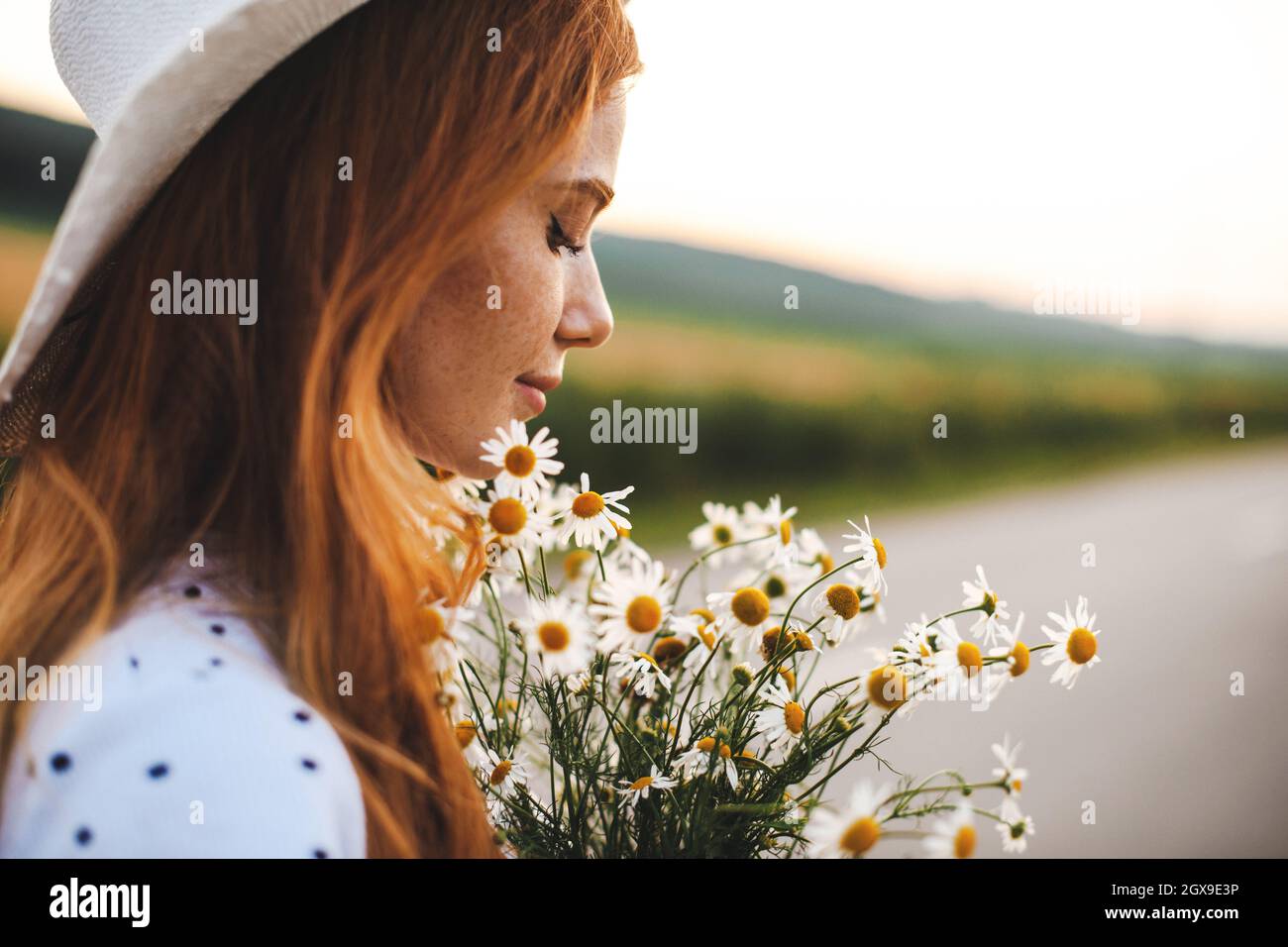 Estate prato fiori. Donna zenzero che tiene un bouquet di fiori. Persona freckled che posa in campo. Foto Stock