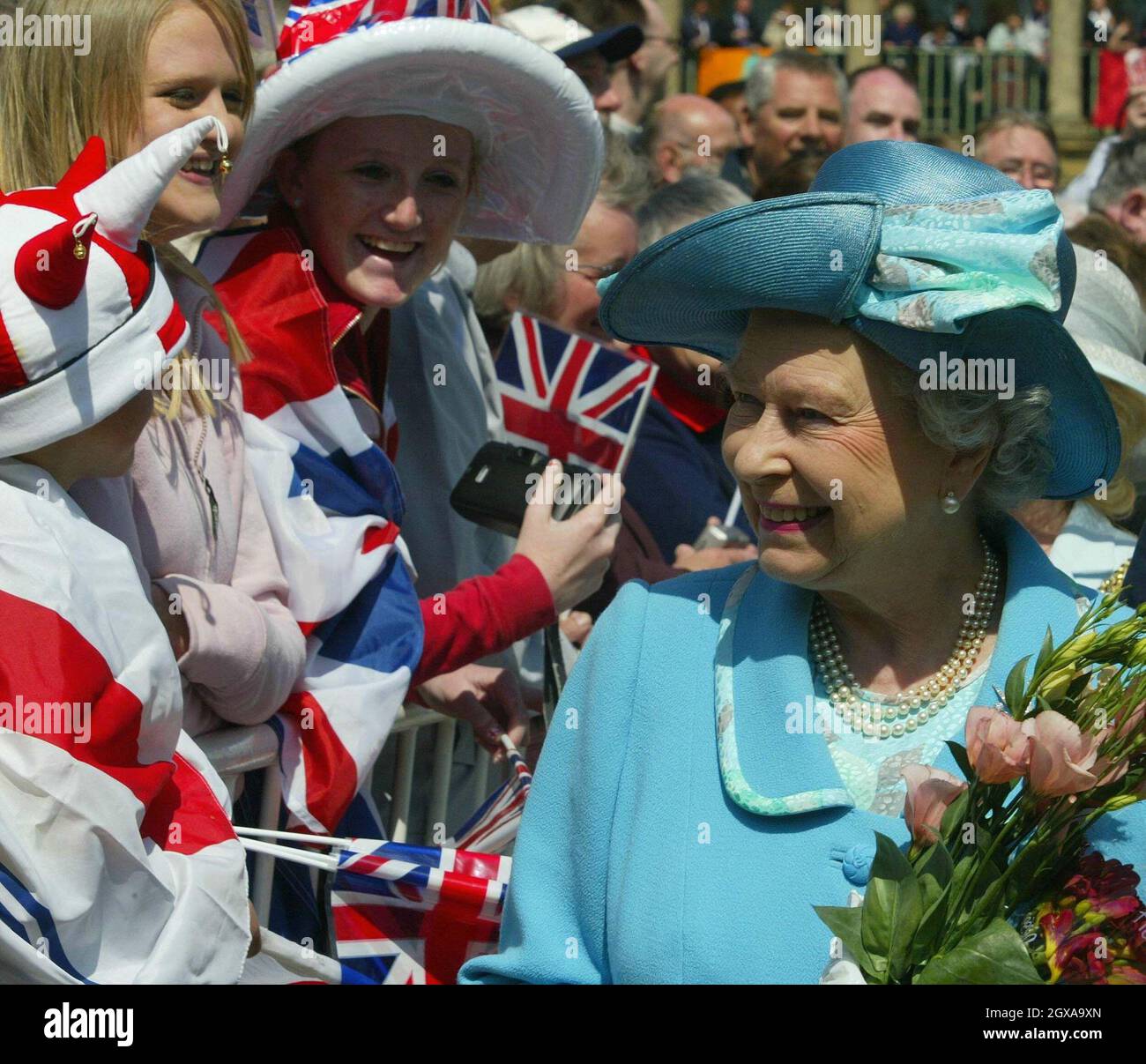 La Regina Elisabetta II della Gran Bretagna incontra i membri del pubblico a Piece Hall a Halifax, Yorkshire, un ex mercato per tessitori locali che è ora un fiorente centro business per piccoli commercianti specializzati in arti creative Giovedi 27 maggio 2004. Lei e il Duca di Edimburgo hanno assistito a una performance di un gruppo teatrale locale specializzato nell'uso del dramma per costruire fiducia nei giovani, E prima la regina fece un giro alla High School di Halifax, dove un allievo di 11 anni le presentò una possia - dopo aver guardato una moneta per vedere chi era. Foto Stock