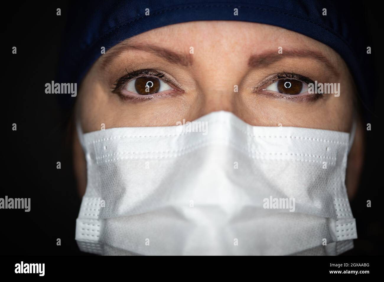 Medico o infermiere che indossa la maschera medica del viso su sfondo scuro. Foto Stock