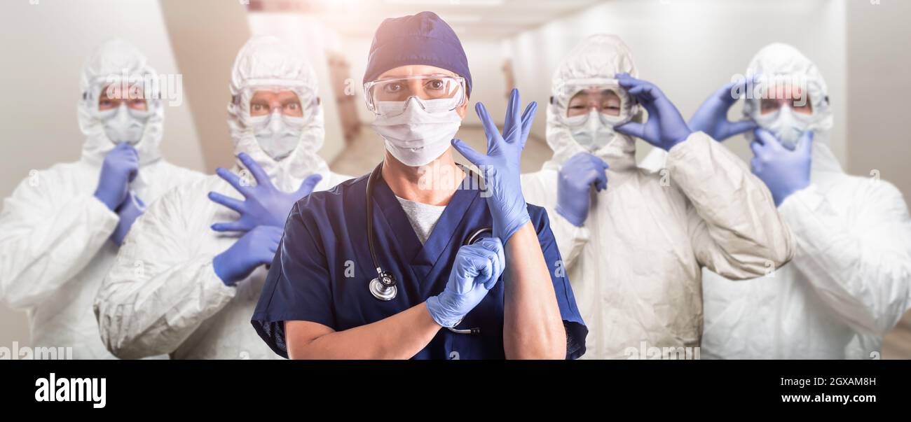 Team di medici o infermieri di sesso femminile e maschile che indossano equiment protettivo personale nel corridoio dell'ospedale Foto Stock