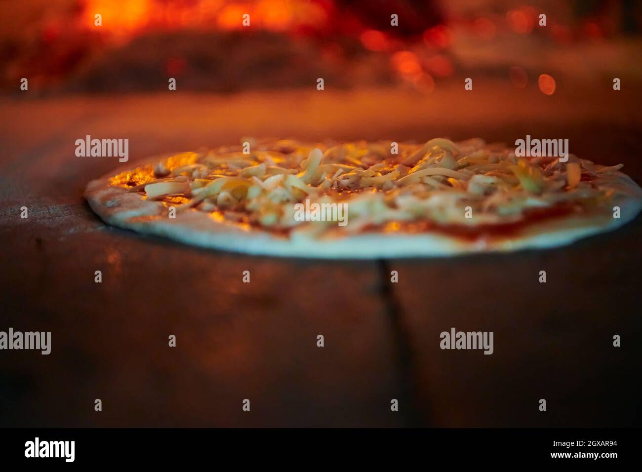 La pizza rustica viene rimossa dalla stufa calda dove è stata cotta. Cuocere con una pala speciale per rimuoverle. Questo ristorante dispone di speciali forno a legna Foto Stock