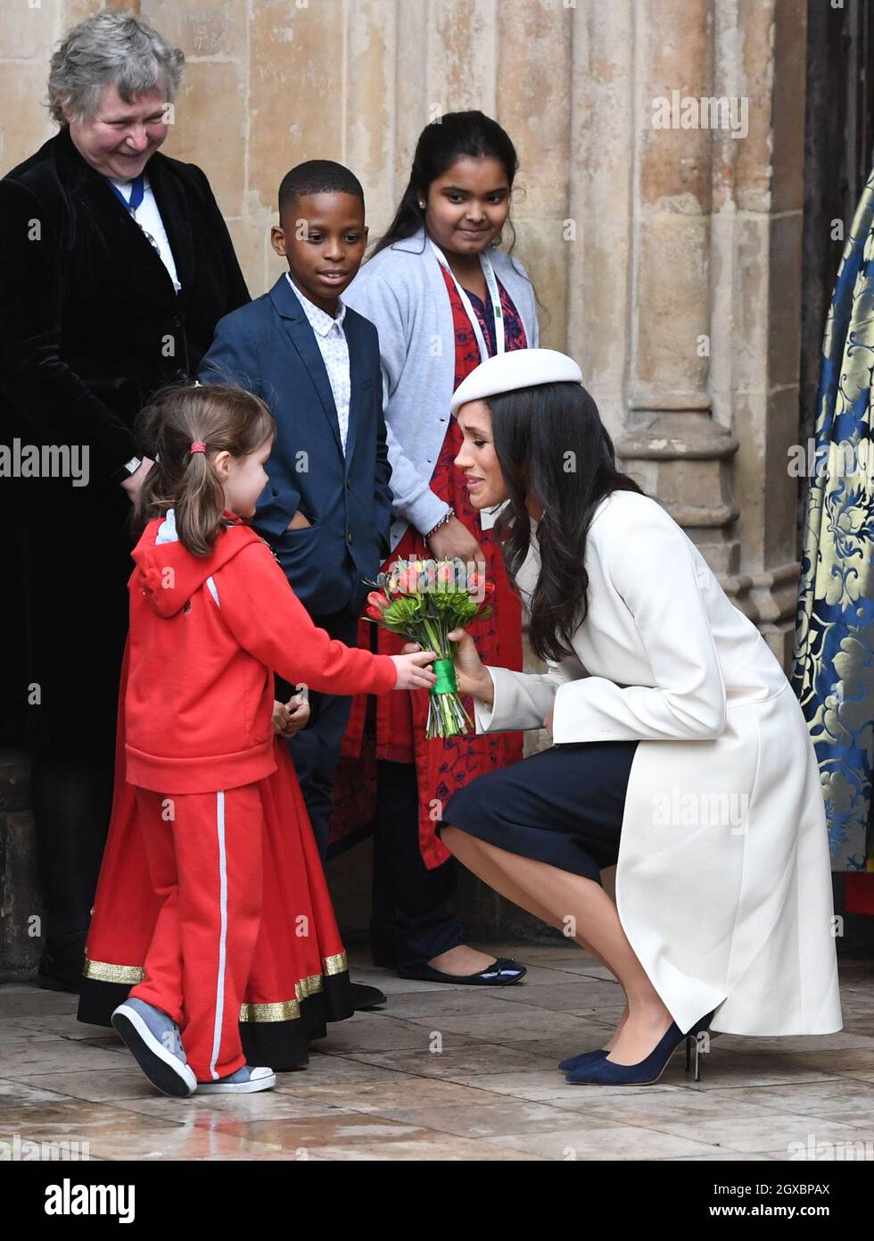 Meghan Markle, indossando un cappotto color crema Amanda Wakeley e un  cappello abbinato, riceve un poso di fiori da una giovane ragazza seguendo  il Servizio del Commonwealth presso l'Abbazia di Westminster a