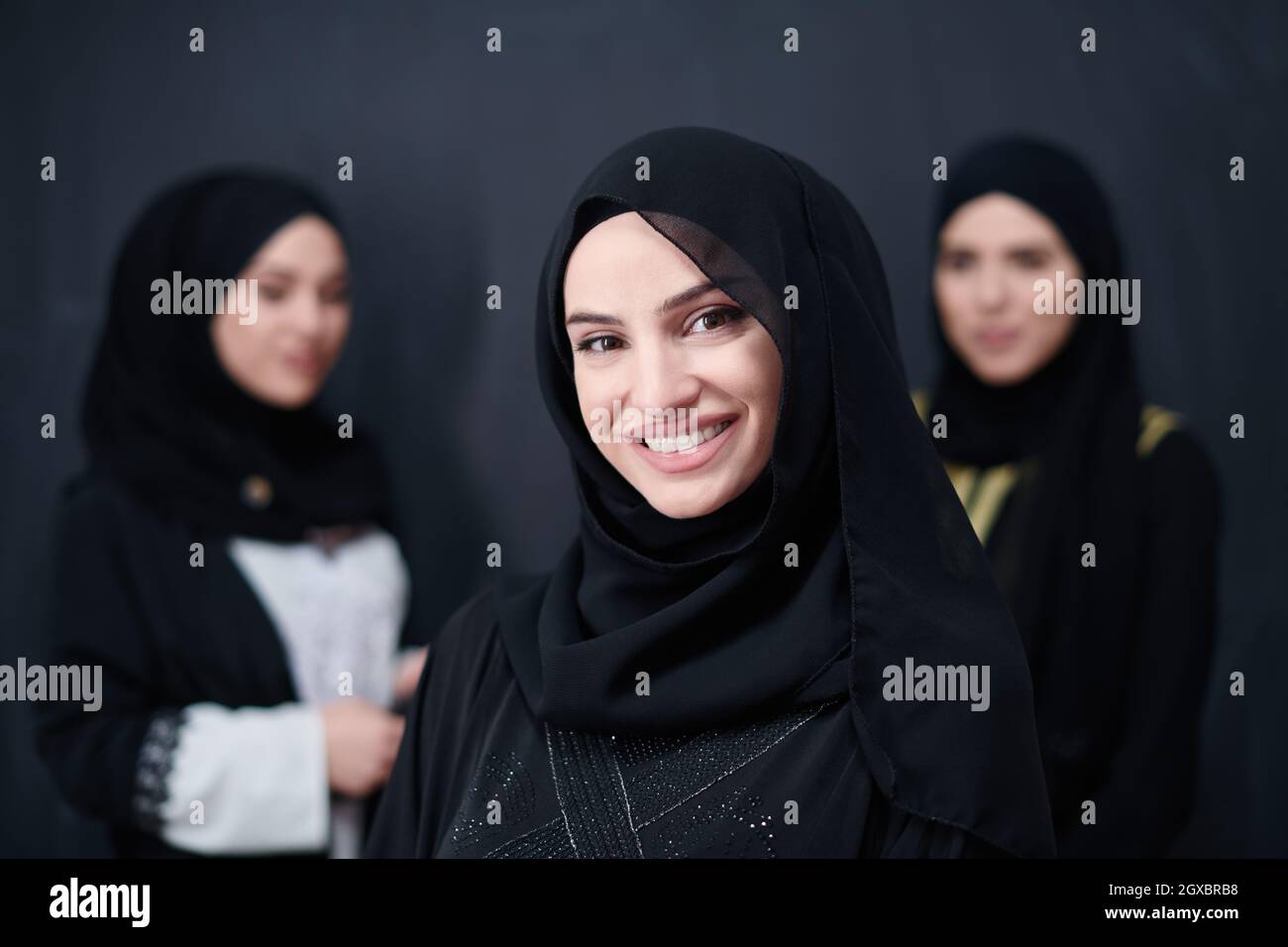 ritratto di gruppo di belle donne musulmane in abito alla moda con hijab isolato su sfondo nero lavagna che rappresenta la moda moderna islam e. Foto Stock