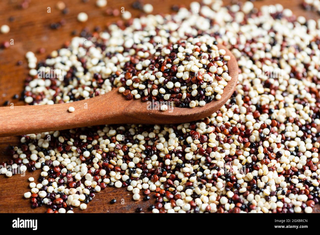 rosso e con la quinoa cruda su cucchiaio di legno Foto Stock