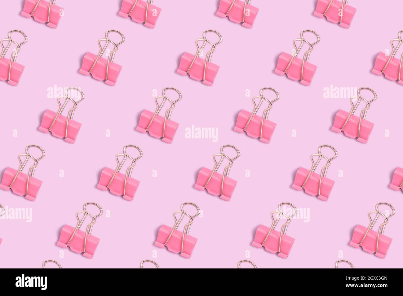 Motivo fatto di clip di carta rosa su uno sfondo viola pastello. Layout creativo. Foto Stock