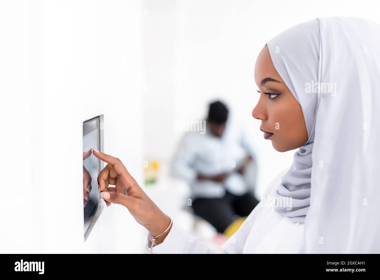 Giovane africana moderna donna musulmana utilizzando smart nella schermata iniziale del sistema di controllo Foto Stock