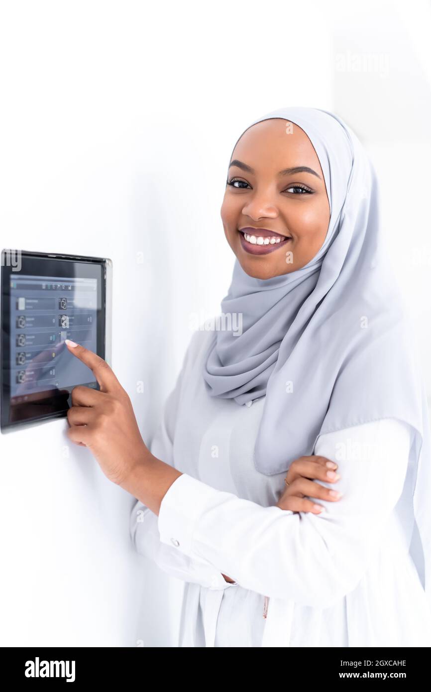 Giovane africana moderna donna musulmana utilizzando smart nella schermata iniziale del sistema di controllo Foto Stock