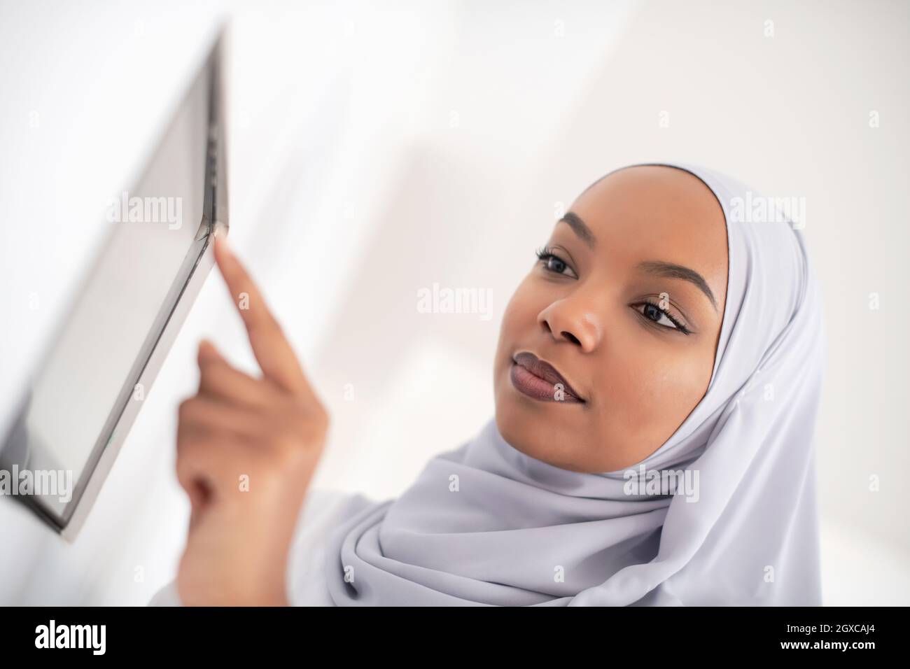 Donna africana che utilizza un sistema di controllo smart home screen Foto Stock