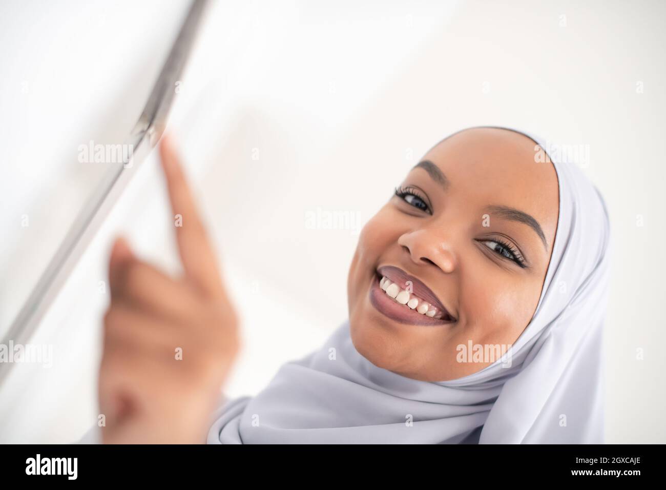 Donna africana che utilizza un sistema di controllo smart home screen Foto Stock
