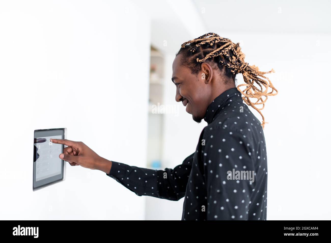 L'uomo africano utilizzando smart nella schermata iniziale del sistema di controllo Foto Stock