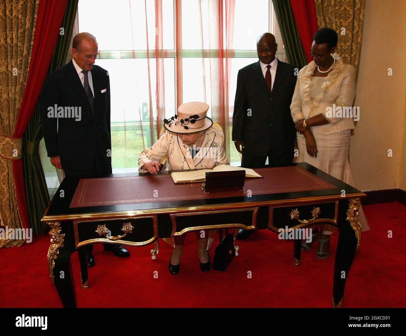 La Regina Elisabetta II firma il libro dei visitatori seguito dal Principe Filippo, Duca di Edimburgo, dal Presidente Yoweri Museveni e dalla moglie Janet presso la state House di Entebbe in Uganda. La Regina aprirà venerdì la riunione dei Capi di Governo del Commonwealth. Alla CHOGM parteciperanno oltre 5000 delegati, il Principe del Galles e la Duchessa della Cornovaglia, nonché il primo Ministro britannico Gordon Brown. Foto Stock