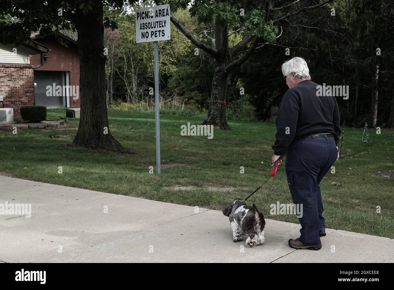 Un uomo cammina un cane oltre un segno che vieta gli animali domestici a una sosta di riposo lungo la i-79 nel nord-ovest della Pennsylvania. Foto Stock