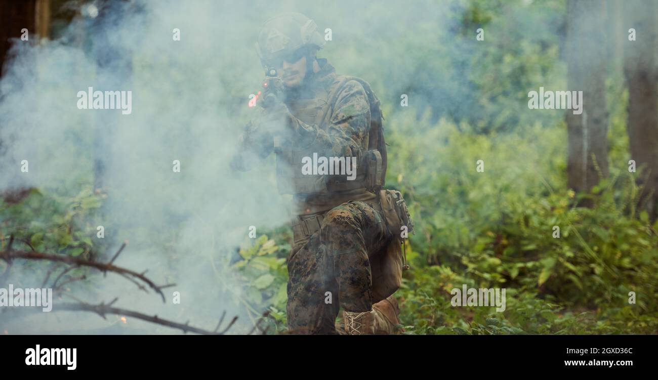 un moderno soldato di guerra in azione che punta all'arma ottica a vista laser in posizione di combattimento mentre cerca un bersaglio in battaglia Foto Stock