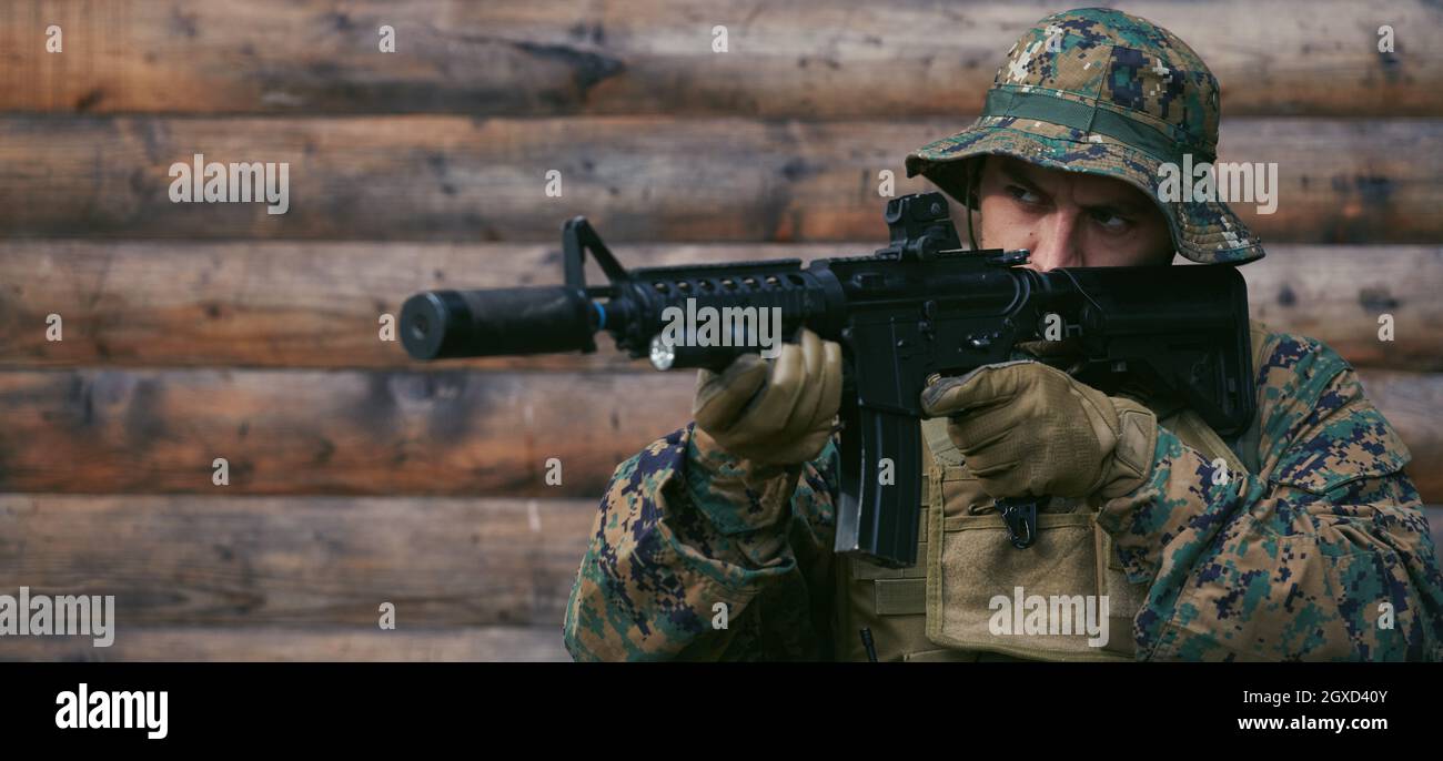 un moderno soldato di guerra in azione che punta all'arma ottica a vista laser in posizione di combattimento mentre cerca un bersaglio in battaglia Foto Stock