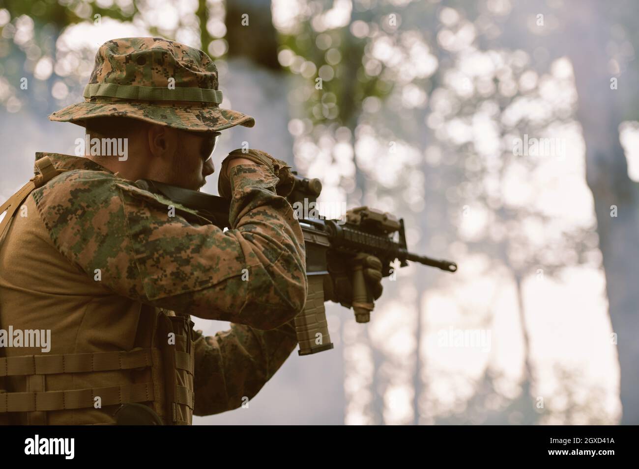 un moderno soldato di guerra in azione che punta all'arma ottica a vista laser in posizione di combattimento mentre cerca un bersaglio in battaglia Foto Stock