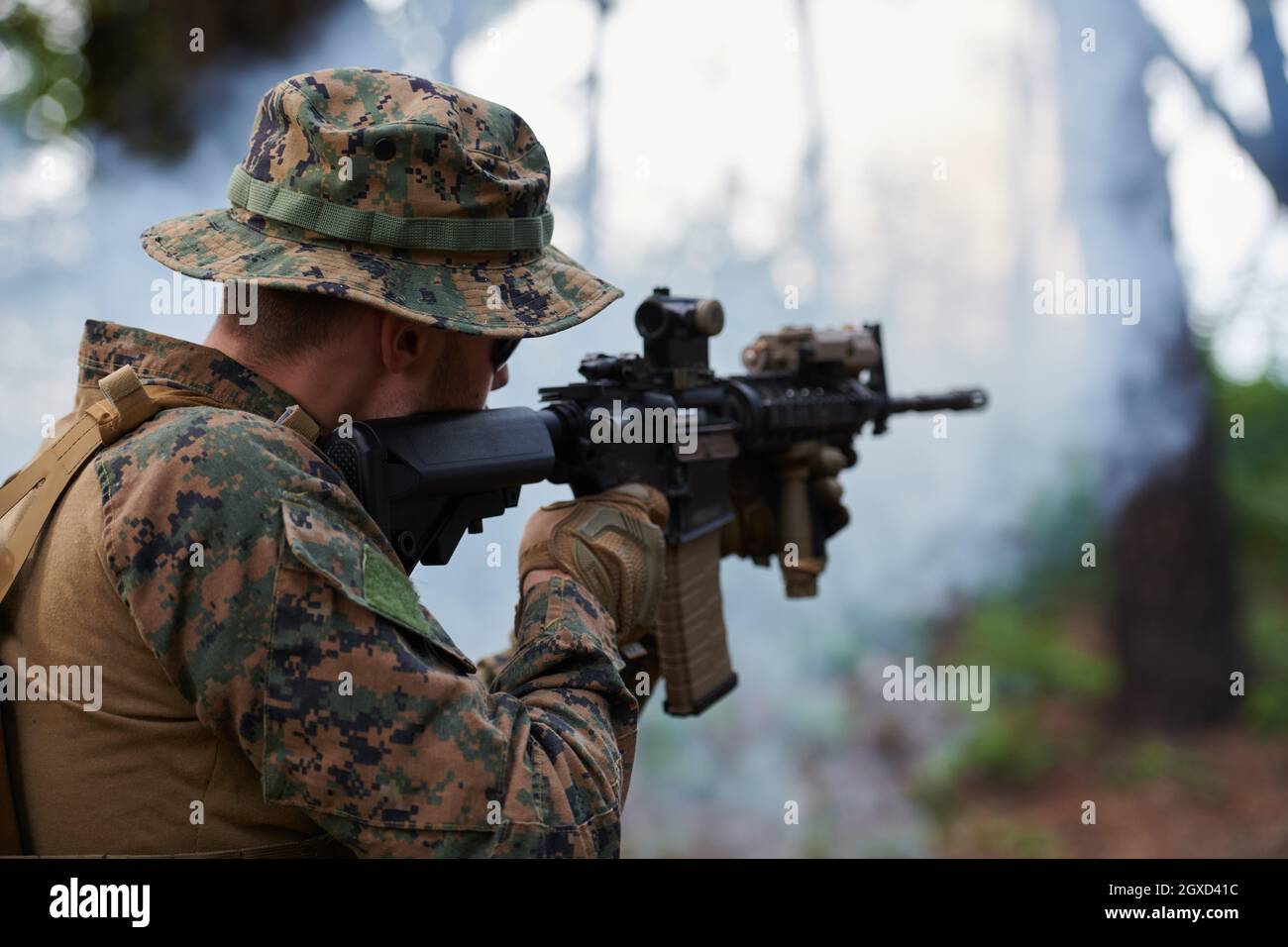 un moderno soldato di guerra in azione che punta all'arma ottica a vista laser in posizione di combattimento mentre cerca un bersaglio in battaglia Foto Stock