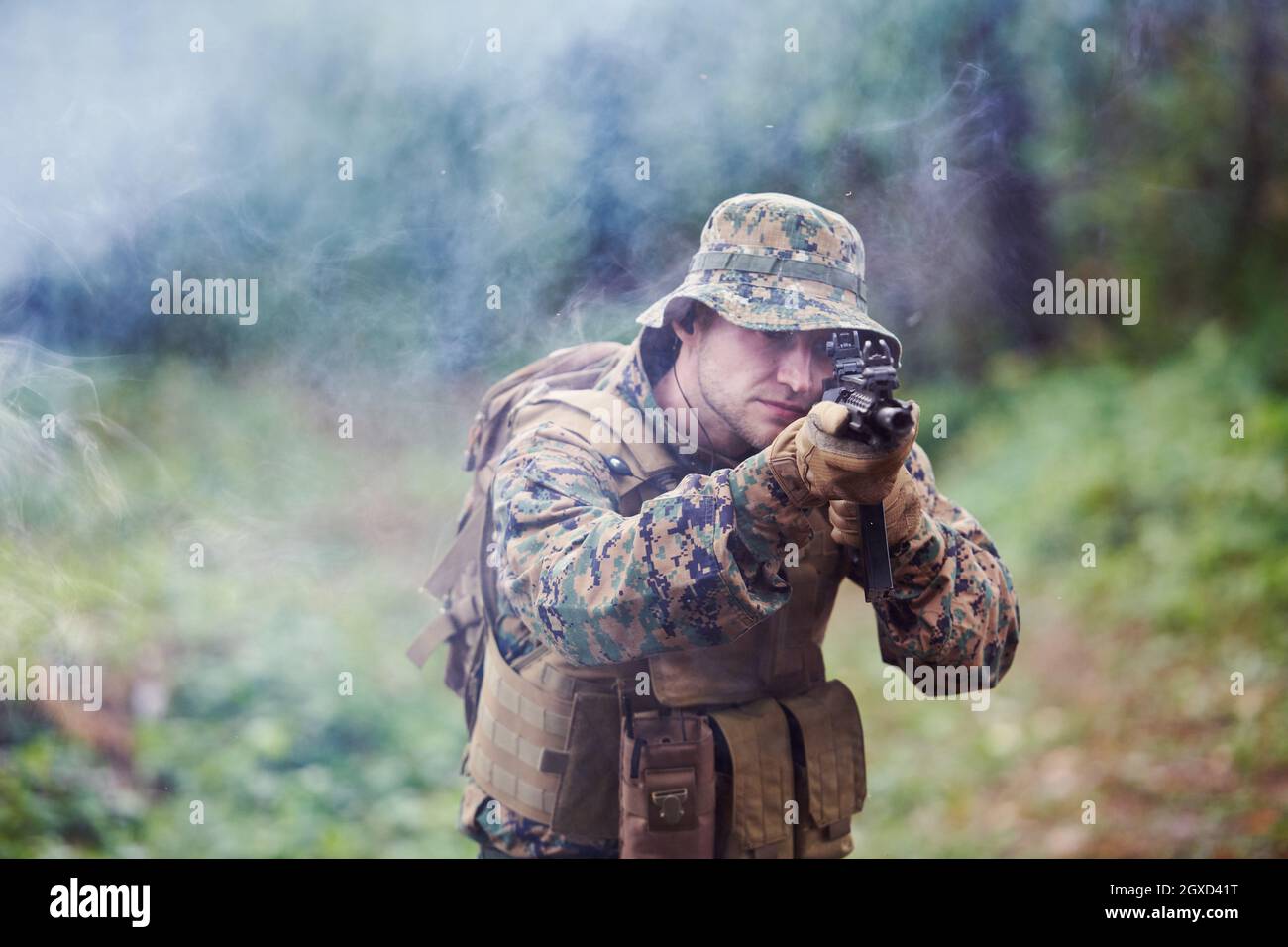 un moderno soldato di guerra in azione che punta all'arma ottica a vista laser in posizione di combattimento mentre cerca un bersaglio in battaglia Foto Stock