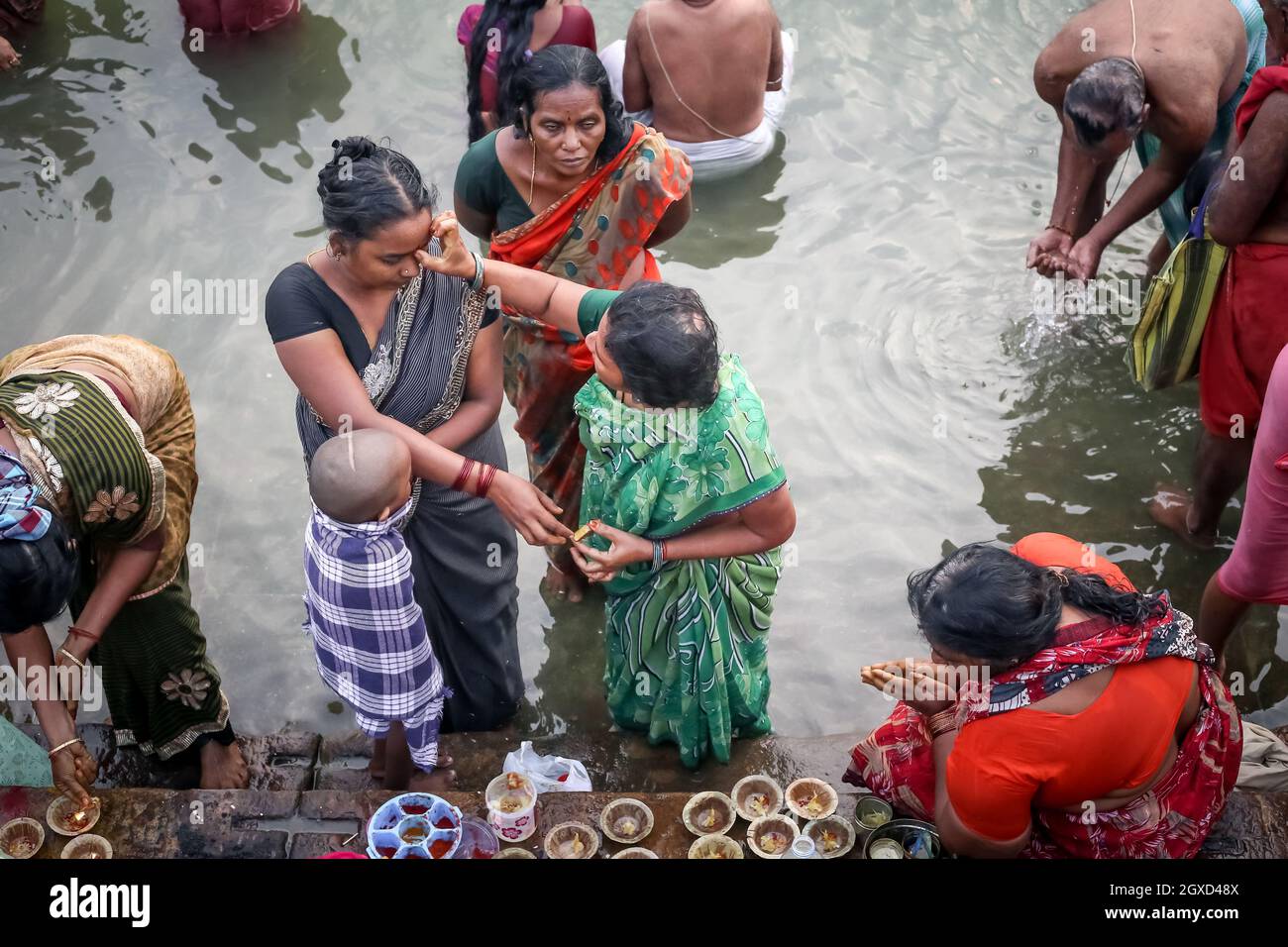 INDIA, VARANASI - 20 NOVEMBRE 2015: Da sopra gruppo di donne etniche in donne asiatiche tradizionali in abiti indiani che pregano e fanno l'offerta Foto Stock