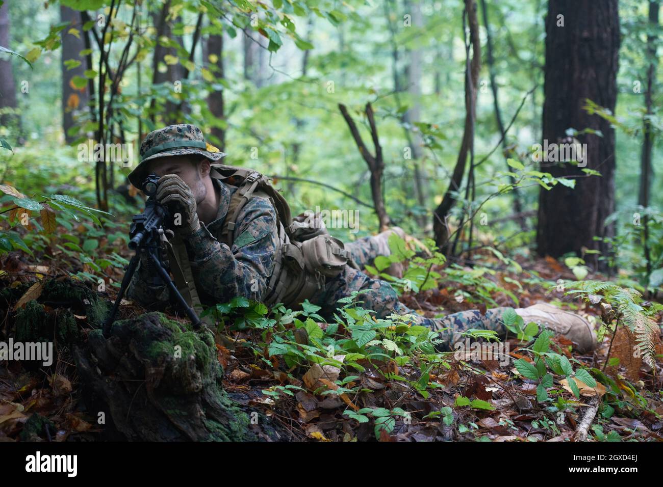 un moderno soldato di guerra in azione che punta all'arma ottica a vista laser in posizione di combattimento mentre cerca un bersaglio in battaglia Foto Stock