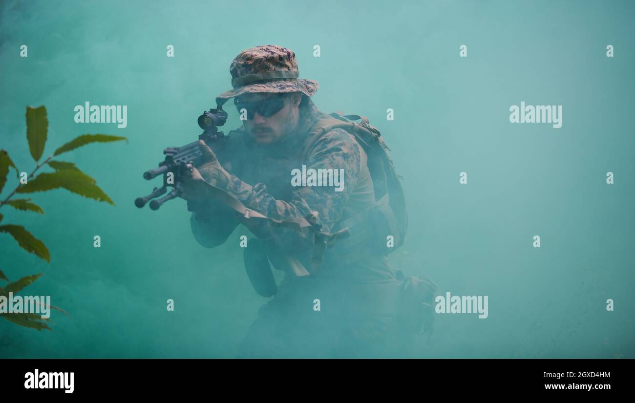 un moderno soldato di guerra in azione che punta all'arma ottica a vista laser in posizione di combattimento mentre cerca un bersaglio in battaglia Foto Stock