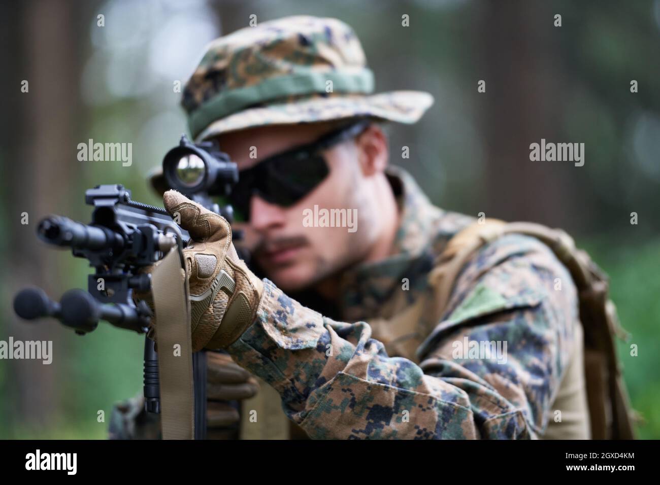 un moderno soldato di guerra in azione che punta all'arma ottica a vista laser in posizione di combattimento mentre cerca un bersaglio in battaglia Foto Stock