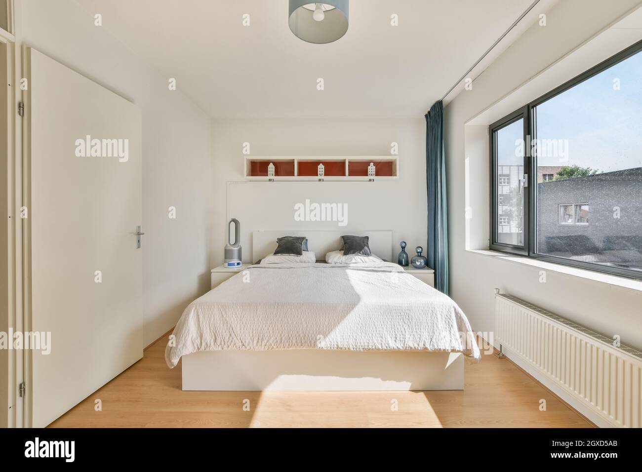 Letto con cuscini sotto la mensola e lampada sopra il parquet in casa  moderna con finestra e radiatore in giorno di sole Foto stock - Alamy
