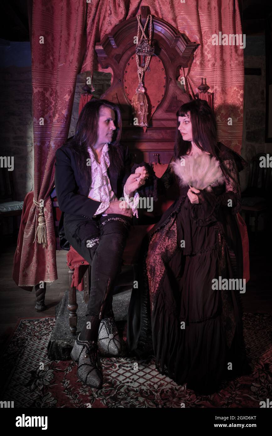 uomo e donna in abiti gotici seduti su un trono in un ambiente medievale. Vampiri. Foto Stock