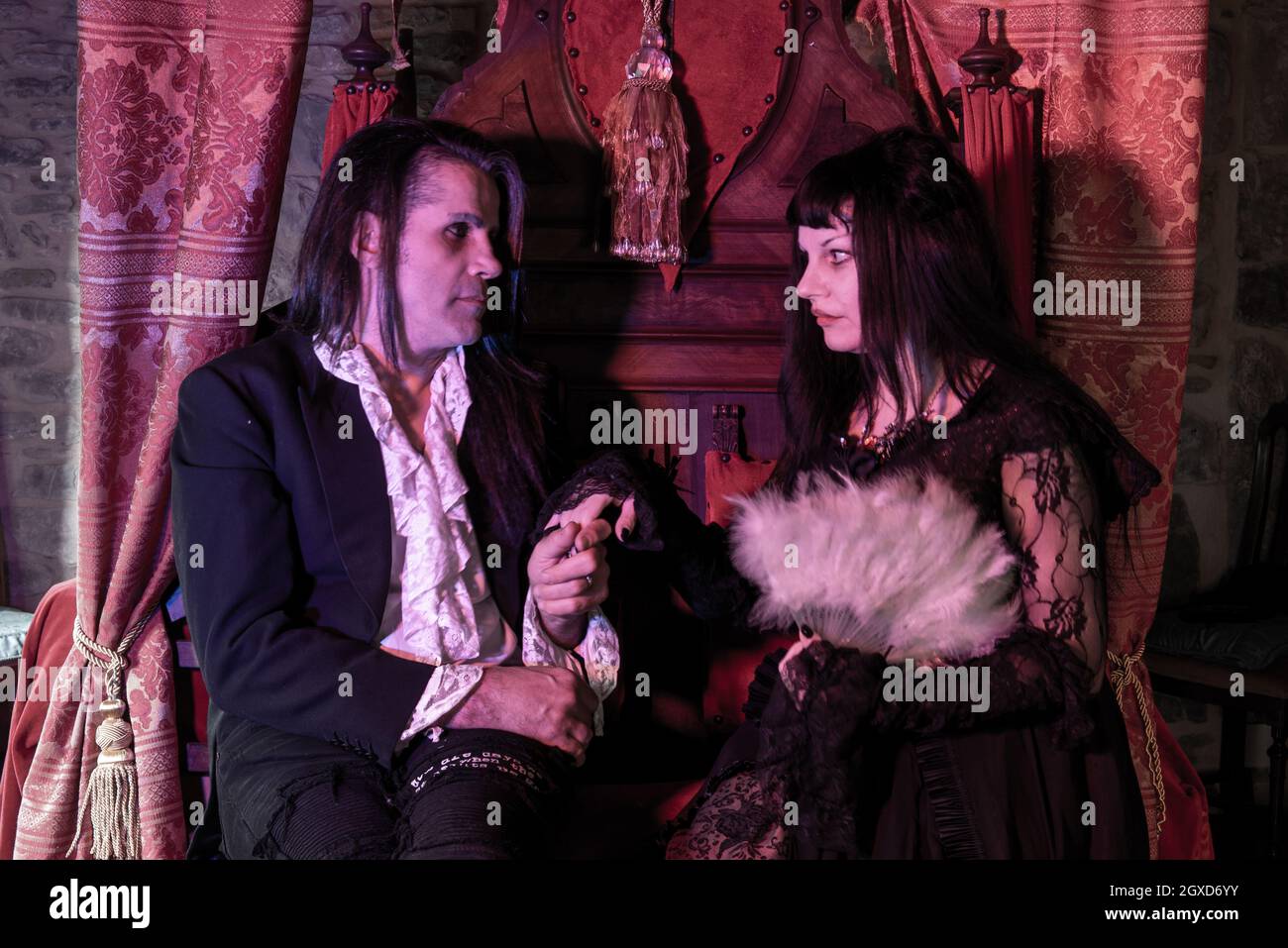 uomo e donna in abiti gotici seduti su un trono in un ambiente medievale. Vampiri. Foto Stock