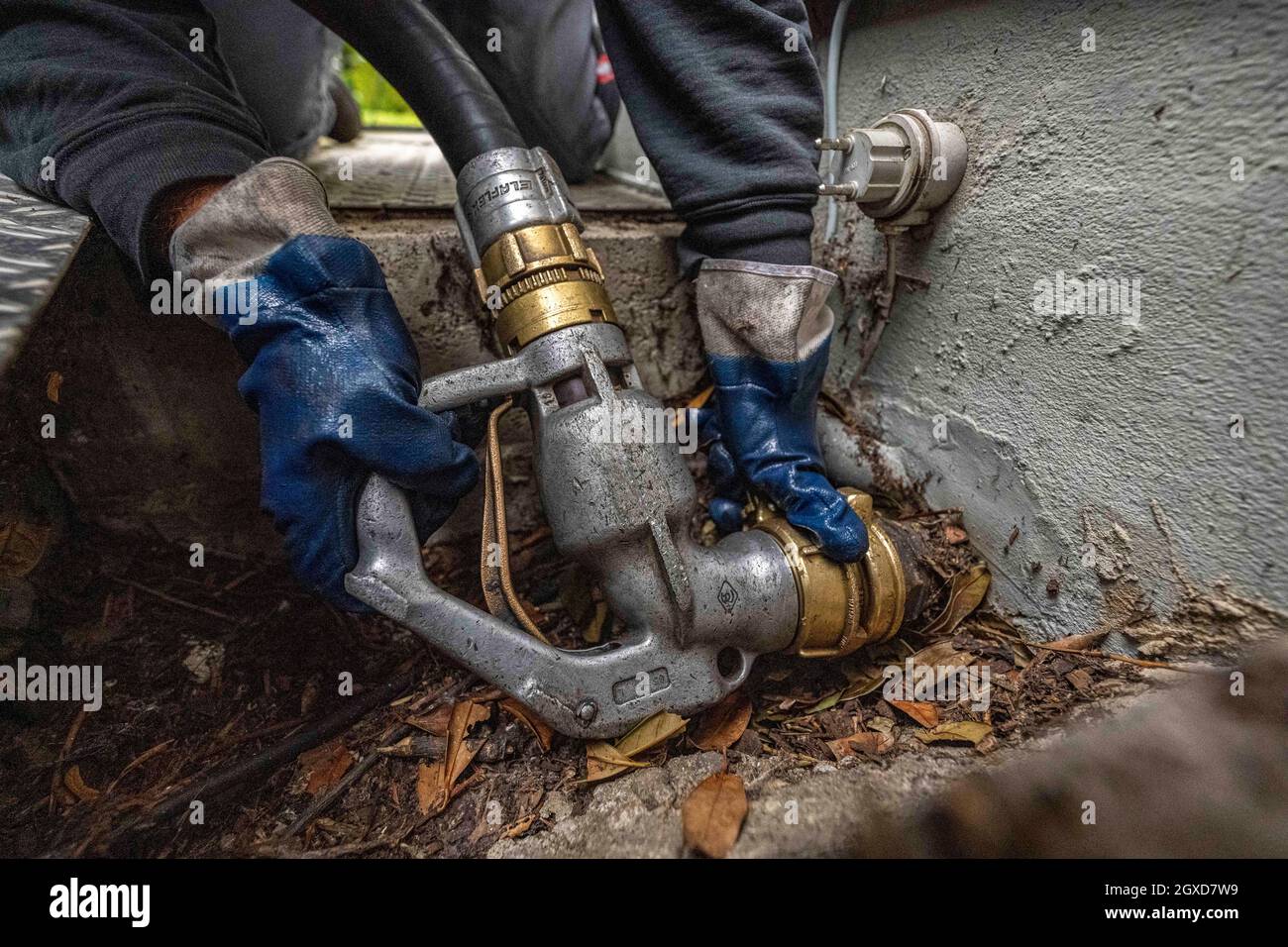 Lippstadt, Germania. 05 ottobre 2021. Un dipendente avvita il tubo flessibile per l'erogazione dell'olio di riscaldamento sul raccordo dell'abitazione. I consumatori possono aspettarsi un forte aumento dei costi di riscaldamento quest'anno a causa dell'elevata domanda globale di petrolio greggio. Sarà ancora più costoso in 2021 nelle case con il riscaldamento di petrolio, dove i costi sono previsti aumentare del 44 per cento - dopo un calo del 27 per cento nell'anno precedente. Credit: David Inderlied/dpa/Alamy Live News Foto Stock