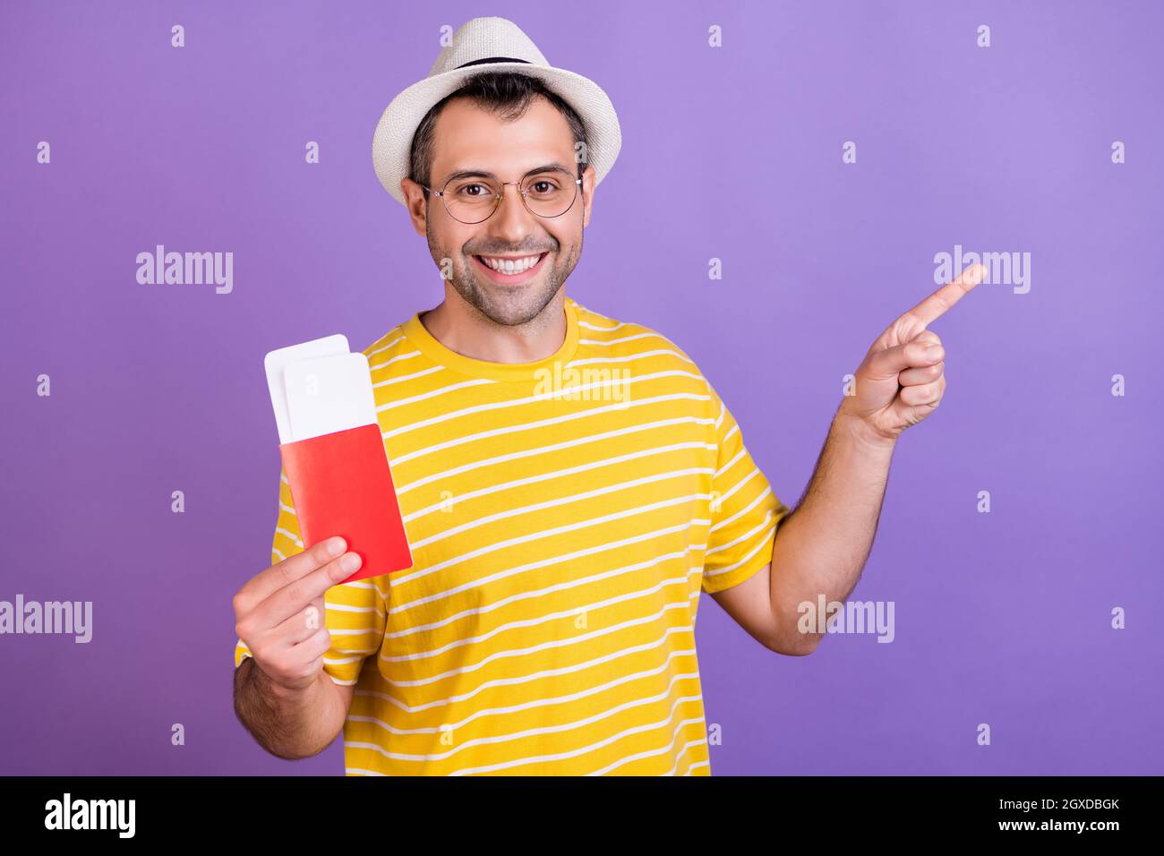 Foto del giovane uomo felice positivo sorriso punto dito vuoto spazio annuncio consiglio biglietti volare all'estero isolato su sfondo di colore viola Foto Stock