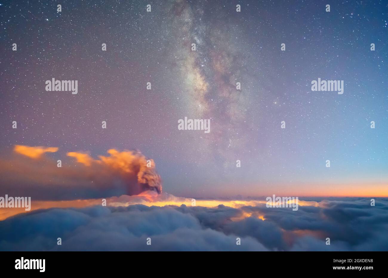 La strada lattiginosa verticale e il vulcano fumano su un mare di nuvole bluastre in una notte stellata. Eruzione vulcanica di Cumbre Vieja nelle Isole Canarie di la Palma, Spagna, Foto Stock
