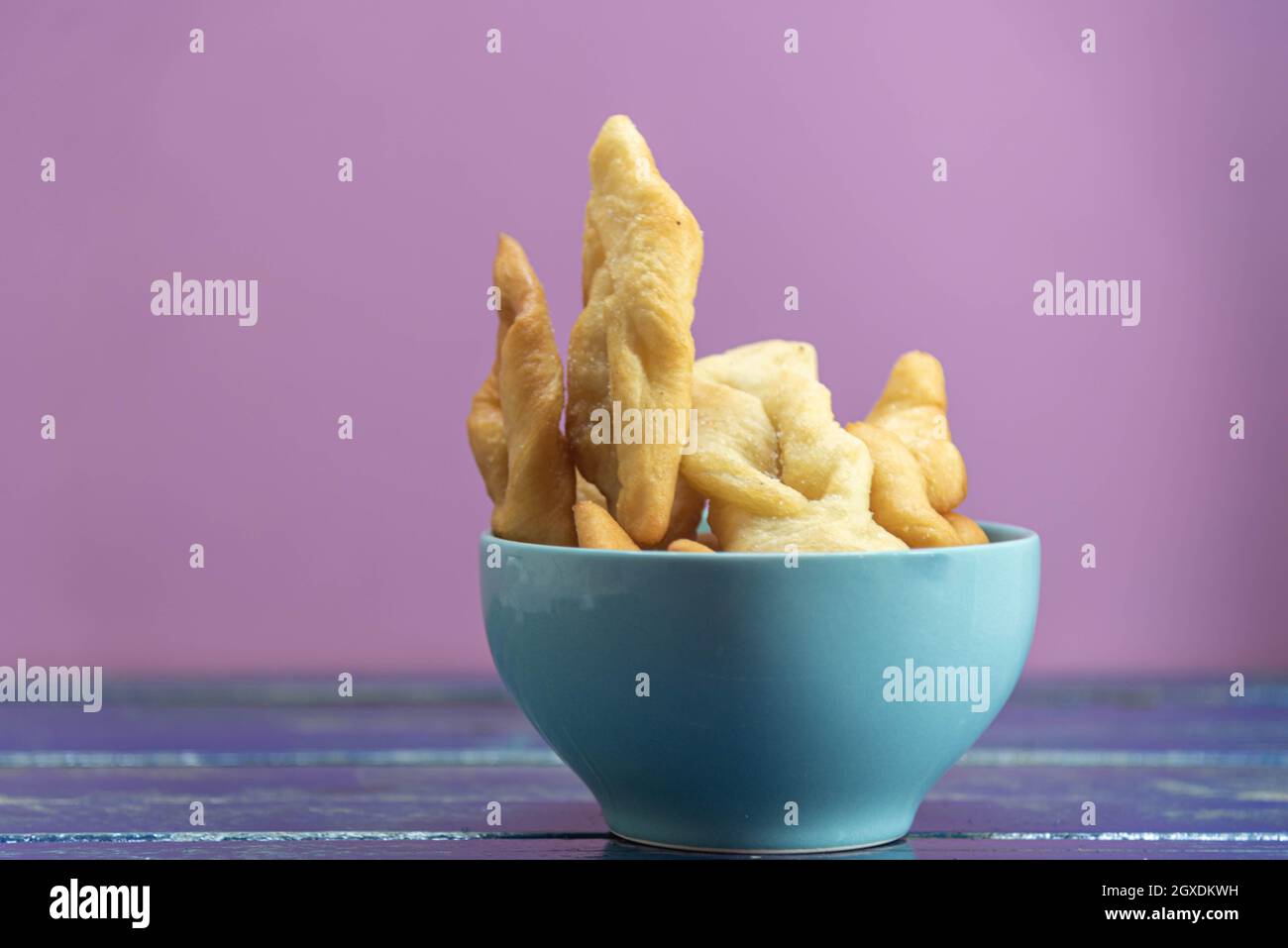 Frappe italiane o chiacchere fatte con pasta di grano in una pentola di porcellana. Prelibatezze e delizie culinarie. Cucina italiana. Impasto di grano fritto con zucchero Foto Stock