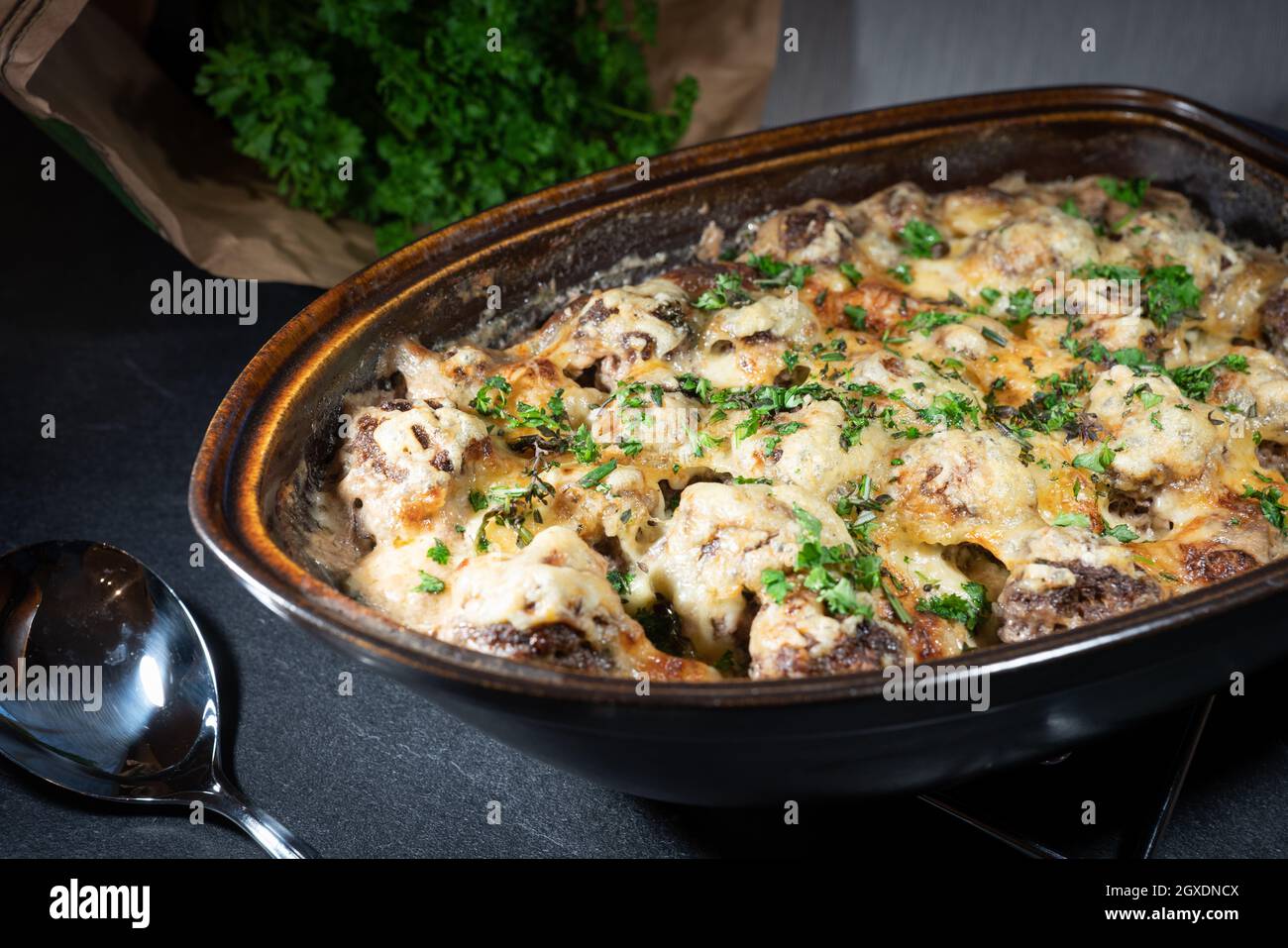 Polpette gratinate in un rustico arrostito con prezzemolo fresco sulla parte superiore e l'erba sullo sfondo Foto Stock