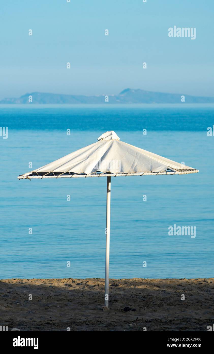 Isola di Sikinos Grecia Spiaggia scena con un ombrello spiaggia vicino al mare Egeo in un giorno d'estate isola di Santorini in lontananza verticale colpo. Foto Stock