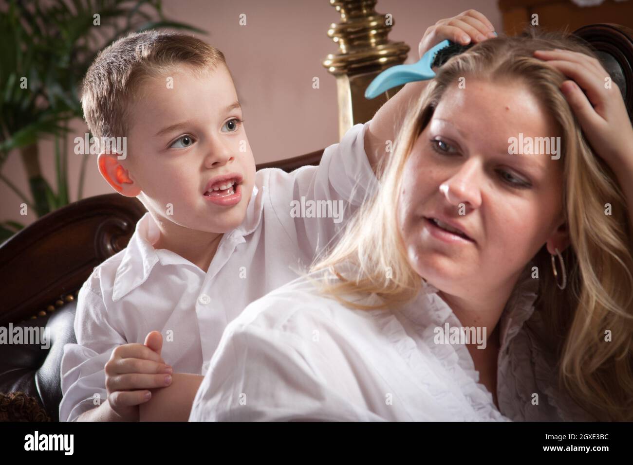 Cute Son spazzolando i capelli di sua mamma in interni. Foto Stock