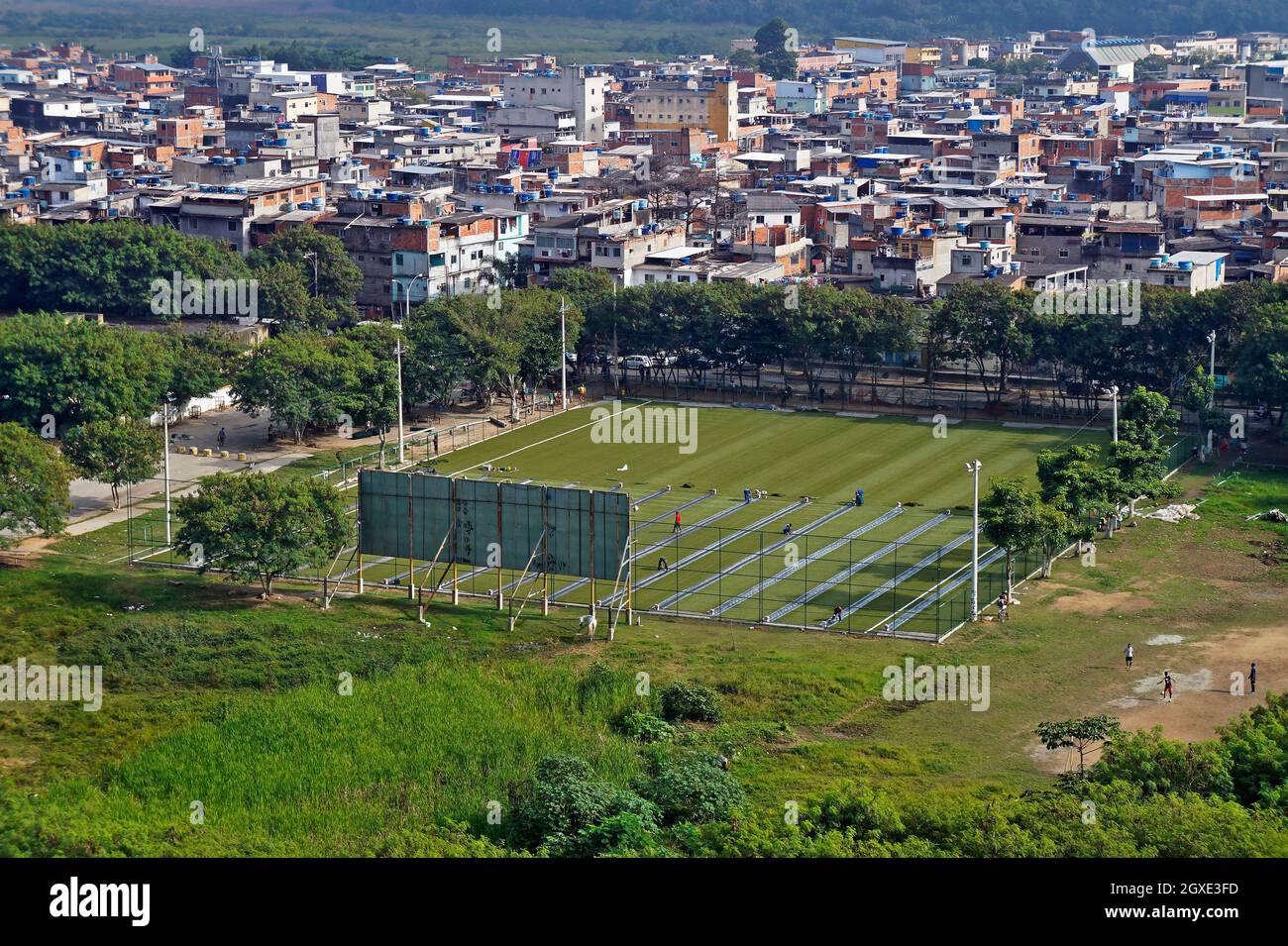 RIO DE JANEIRO, BRASILE - 7 GIUGNO 2014: Applicazione di erba sintetica su un campo di calcio in favela (Rio das Pedras) Foto Stock